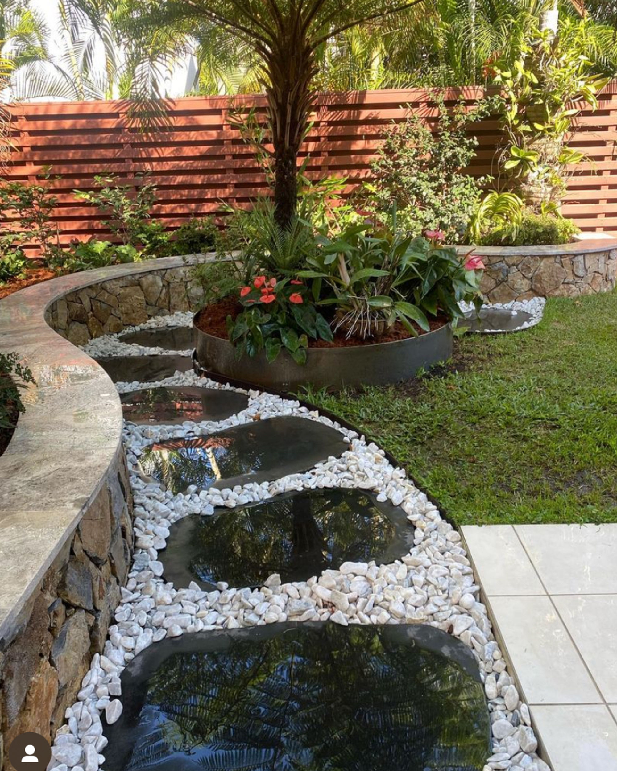 Lush tropical garden with water feature and white pebbles in Kelvin Grove